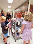 Students picking books from cart.